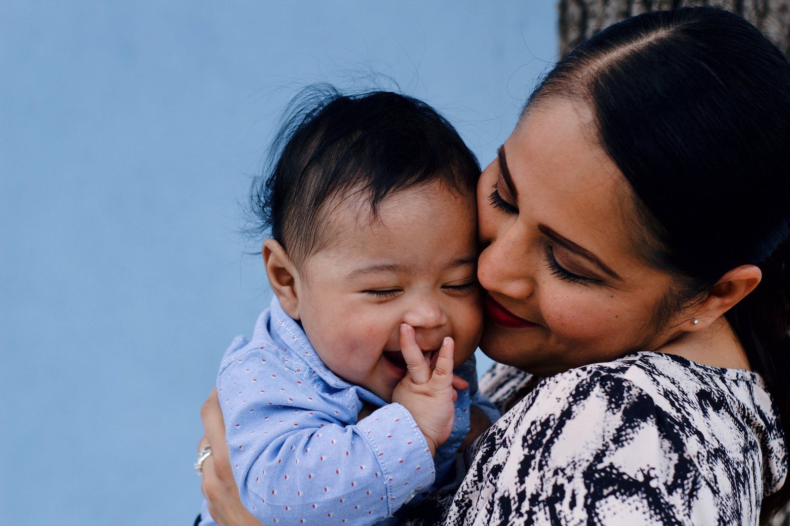 close up photo of smiling woman carrying her smiling baby